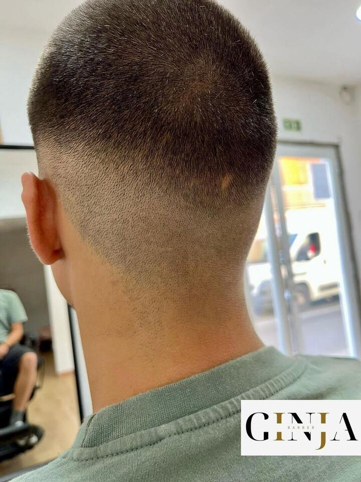 Corte curto à máquina com degradê baixo na nuca