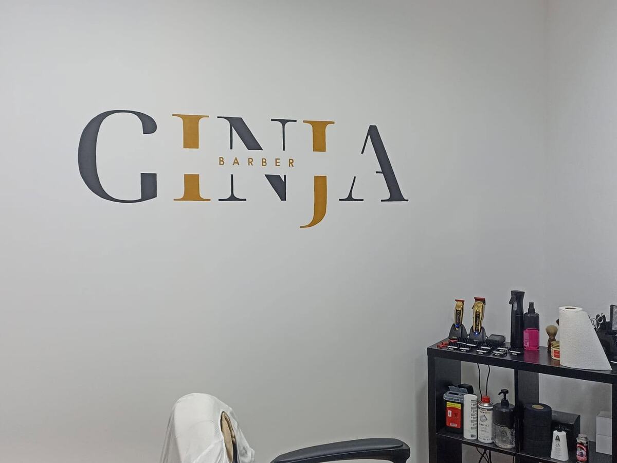 Interior da Ginja Barber na Maceira, com o logótipo pintado na parede e a bancada de trabalho